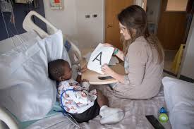 A hospital teacher helps a child learn the alphabet.
